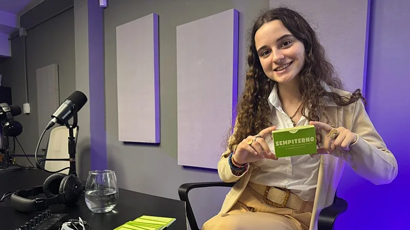 Jimena Zurschmitten sosteniendo el juego de cartas Sempiterno en un aula de San Jerónimo Norte