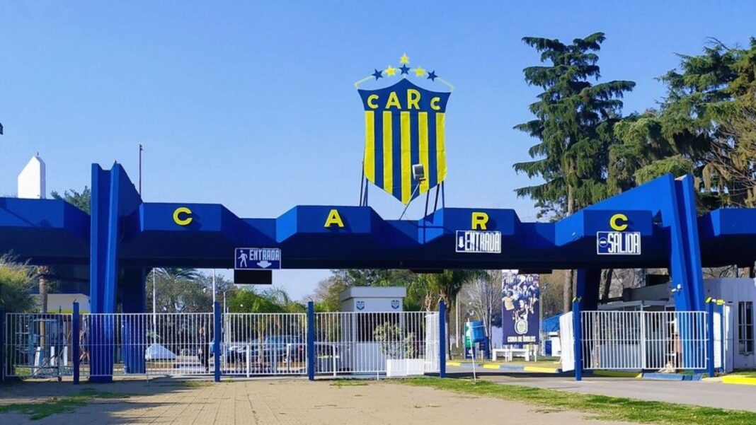 Escudo de Rosario Central junto a jugadores juveniles en el campo de entrenamiento