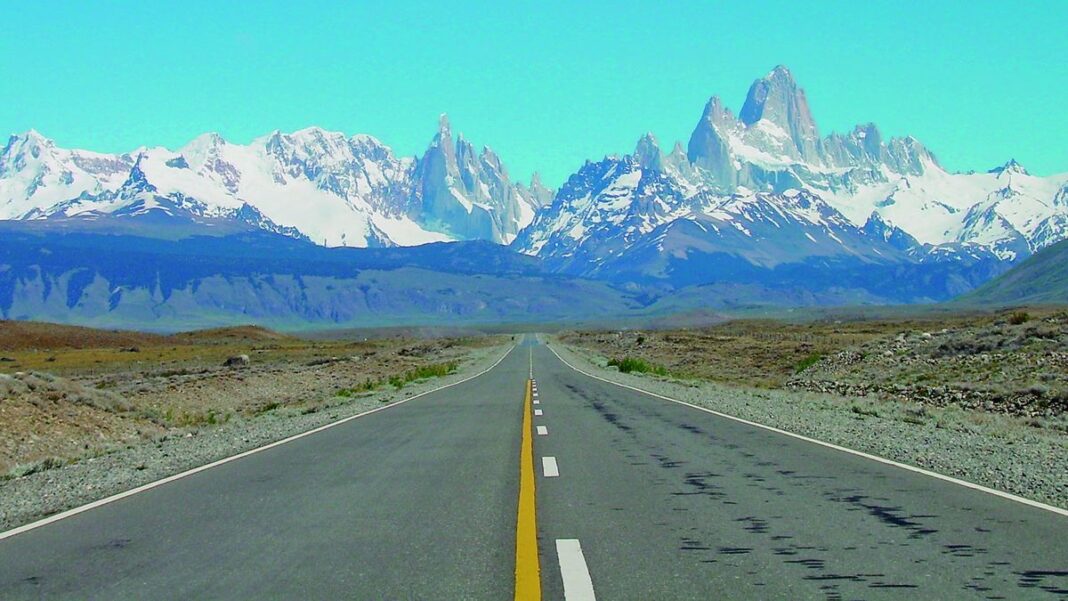 Persona consultando un celular frente a un mostrador de aeropuerto, simbolizando la digitalización del turismo.