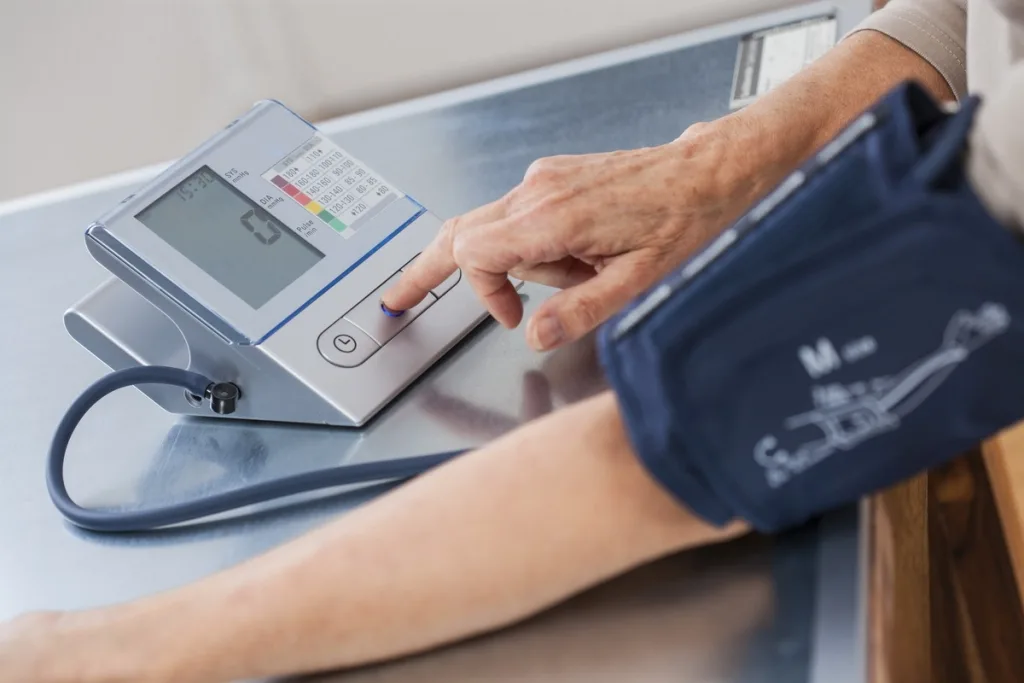 Persona midiéndose la presión arterial con un tensiómetro en el brazo