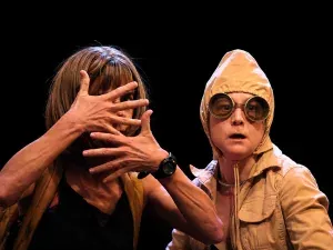 Escena de la obra Hervidero con dos actrices en un espacio con percheros