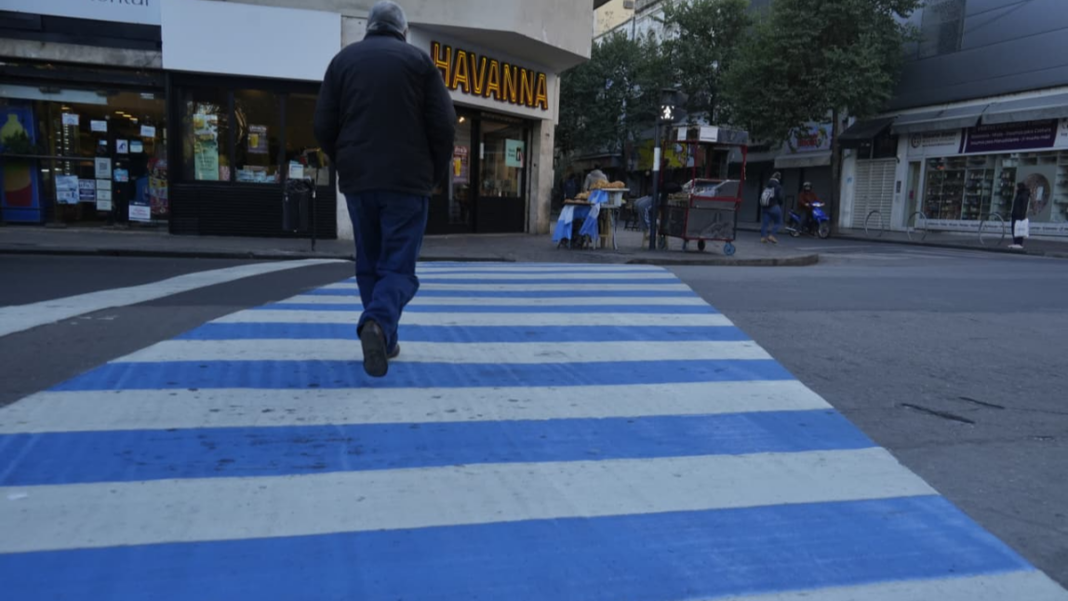 Personas caminando por una peatonal de Rosario con camisetas de la selección argentina y banderas celestes y blancas