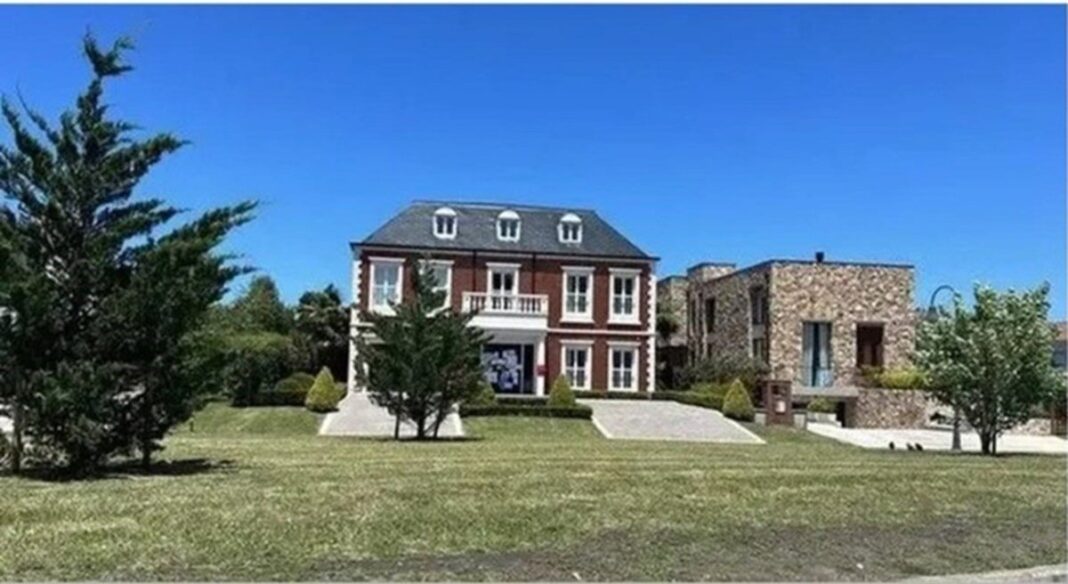 Vista exterior de la casa de Emiliano Dibu Martínez en Mar del Plata, rodeada de vegetación y con grandes ventanales