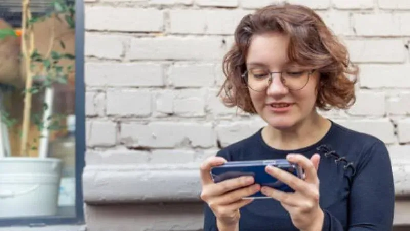 Persona usando teléfono celular con postura inclinada, ilustrando el cuello tecnológico