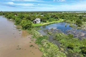 Calle de tierra en Colastiné Sur con vecinos trasladando pertenencias ante la crecida del río Paraná